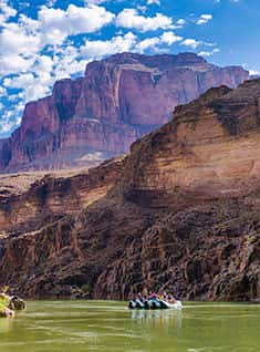 Rafting at the Grand Canyon with towering cliffs and boat floating